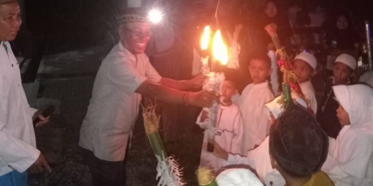 Kadir Sangketa, SH. Lurah Kalaka Kecamatan Bunta Melakukan Pemasangan Obor Terhadap Peserta Pawai .(Dok.ist)