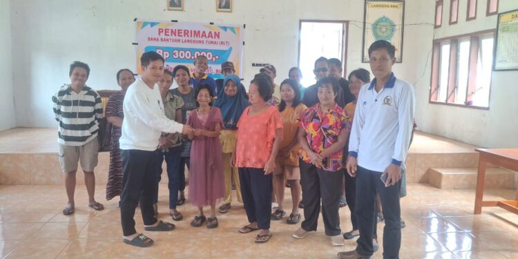 Meixen Poguman Kepala desa tombongan ulos, kecamatan Bunta serahkan BLTDD ke sejumlah masyarakat di dampingi oleh ketua BPD Yulius Galaan. (Dok. ist)