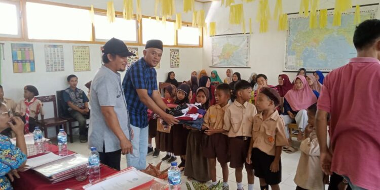 Zulkifli Kairupan Kades tetesulu saat menyerahkan seragam sekolah kepada murid SD. (Dok.ist)